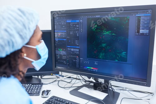 Preview: Researcher Looks At Results From Microscope On Pc Monitor While Searching For Covid-19 Vaccine