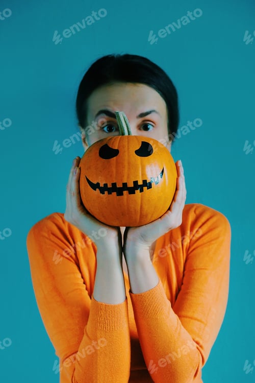 Preview: Woman Holding a Carved Pumpkin in Front of Face