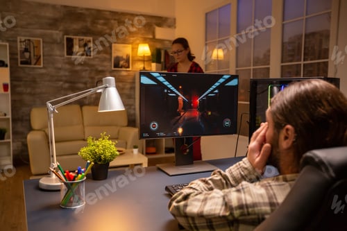 Preview: Back view of professional video gamer playing on powerful PC late at night in the living room