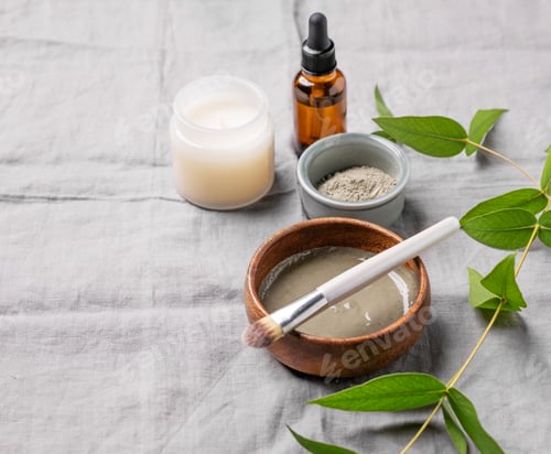 Vista previa: Organic cosmetic with blue clay, serum, brush, candle and branch on a linen background.