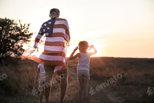 Preview: A happy family with an American flag at sunset.