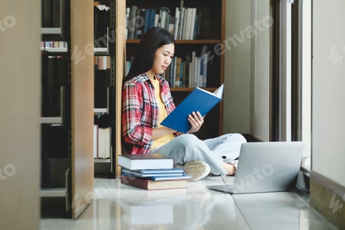 Preview: Young university student using laptop for online learning, searching and learning at library.