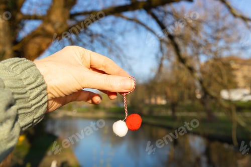Preview: A traditional martisor in a girl's hand against the backdrop of a blurred park.