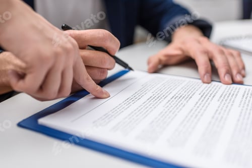 Preview: cropped shot of client signing contract while manageress pointing at it