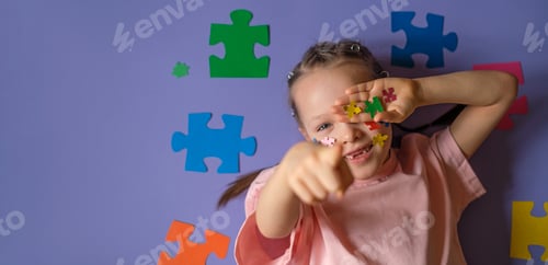 Preview: A girl with a lot of pieces of colorful puzzles in hand points finger forward.