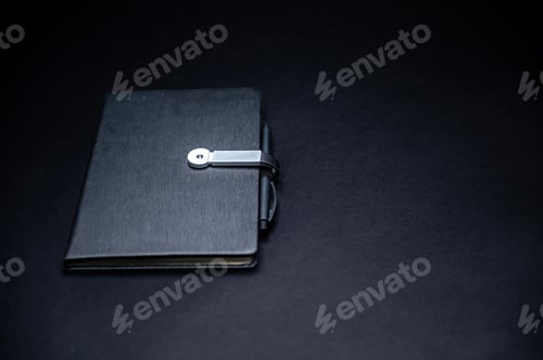 Preview: black planner or notebook with pen isolated on black background, mockup, copy space
