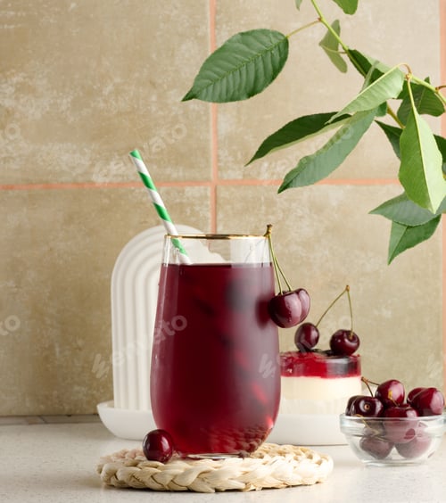 Preview: Cherry juice in a transparent glass and fresh cherries on a white table