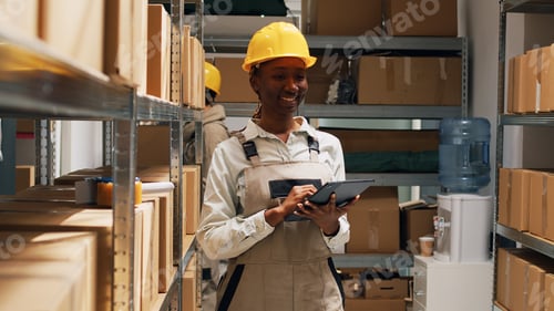 Preview: African american woman in overalls working with tablet