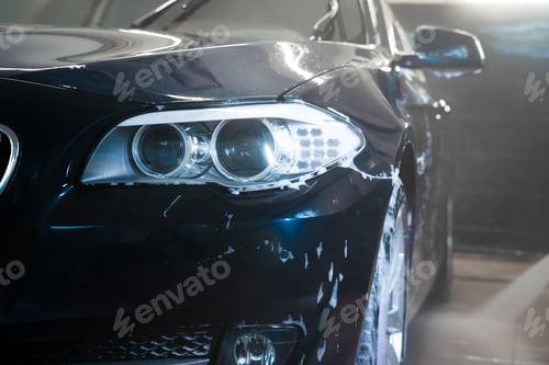 Preview: Auto at the car wash. Flushing foam from car with pressure washer