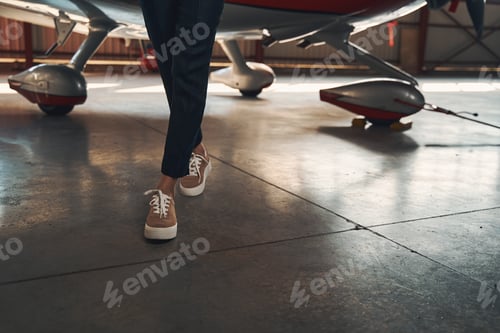 Preview: Female legs in sneakers walking down aircraft hangar