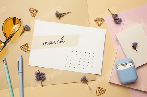 Preview: Flat Lay of March Calendar with Sunglasses, Earbuds, and Spring Flowers on Beige Background