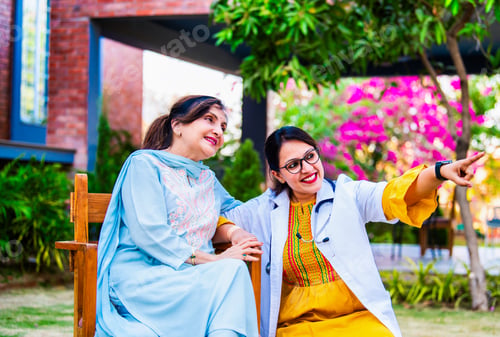 Preview: Young Indian doctor greeting and consulting an elderly patient sitting outside a hospital building