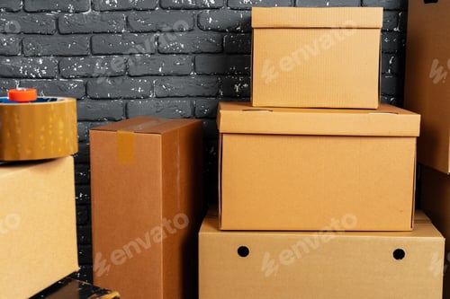 Preview: Stack of cardboard boxes in the empty room against black brick wall