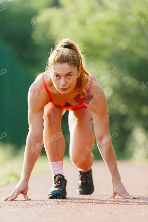 Preview: Athletic woman starting sprint on outdoor track