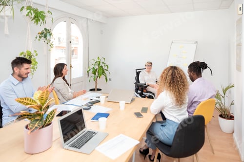 Preview: a businesswoman with a disability sitting in a wheelchair leads a business meeting in a boardroom