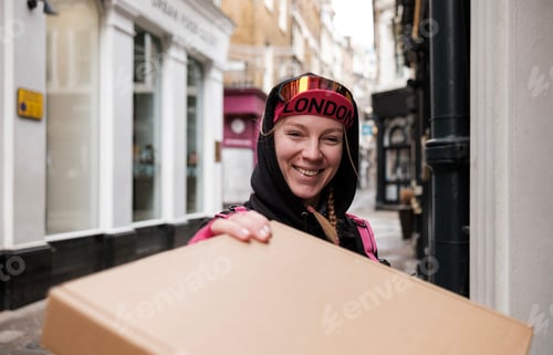 Preview: Smiling bike courier delivering a parcel in the street.