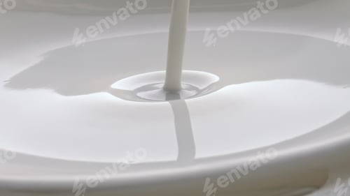 Preview: White yoghurt pouring container closeup. Cold milk cocktail jet filling glass