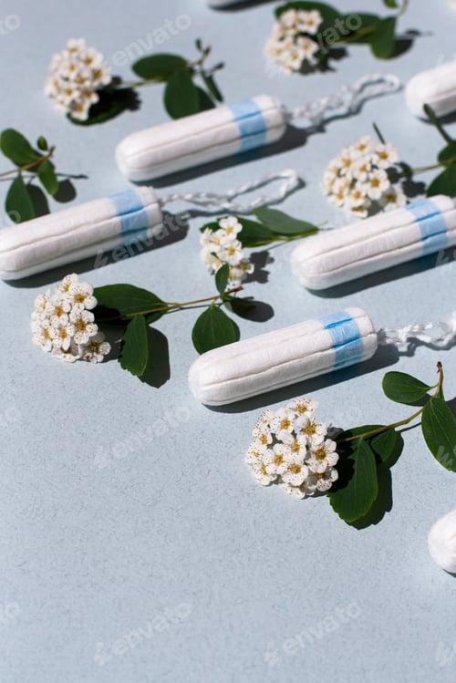 Preview: Medical female tampon and white flowers on a blue background.