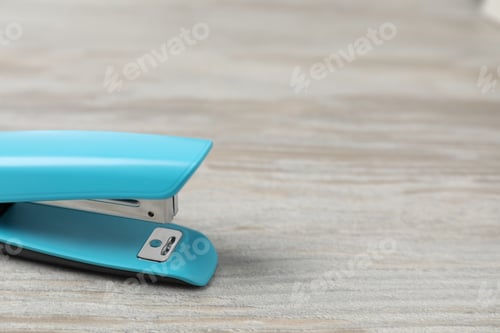 Preview: One light blue stapler on wooden table, closeup. Space for text