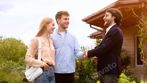 Preview: Cheerful realtor shaking hands with clients in front of residential building outdoors, free space