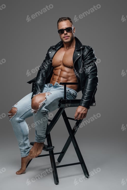 Preview: Strong and stylish man sitting on chair against grey background