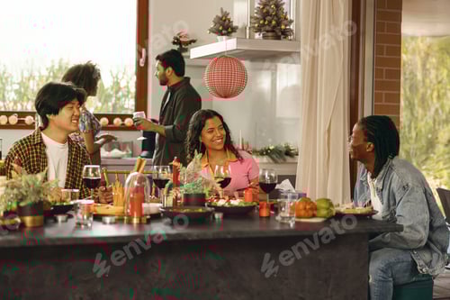 Preview: Happy young friends drinking red wine and enjoying time together at holiday party at home