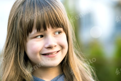 Preview: Portrait of pretty child girl with gray eyes and long fair hair smiling outdoors on blurred green