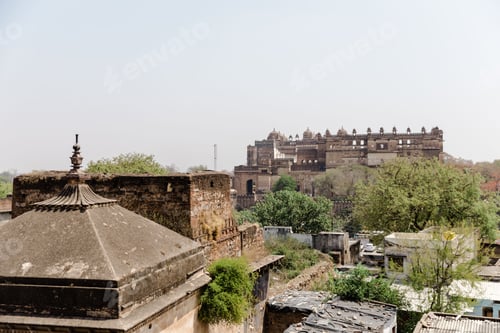 Preview: Aerial view of Orchha Fort in India in the distance, sunlit with a clear blue sky