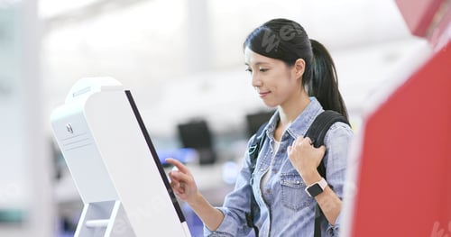 Preview: Woman using selfie check in machine in the airport