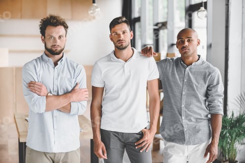 Preview: multiethnic young businessmen looking at camera while standing in office