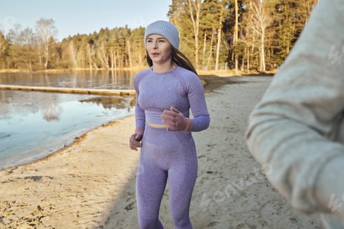 Preview: Adult caucasian woman jogging on beach by the lake in the winter