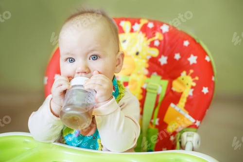 Preview: baby drinking from bottle sitting in the high chair