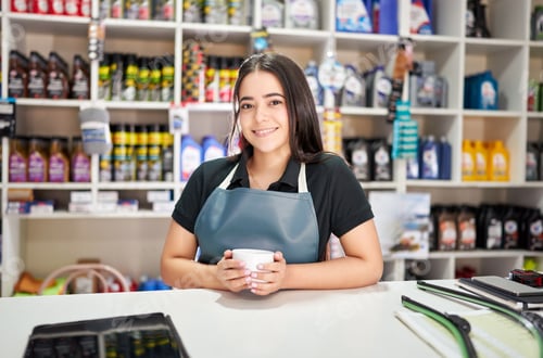 Preview: smiling latin american woman salesperson of a small auto parts store holds a cup of coffee