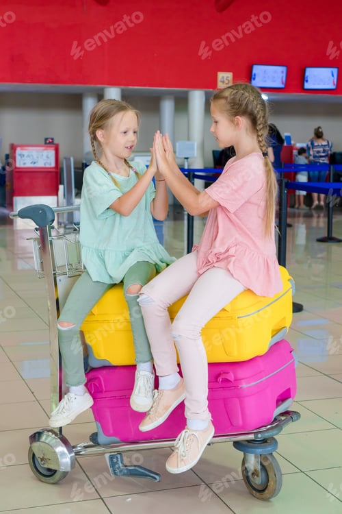 Preview: Adorable little girls having fun in airport waiting for boarding