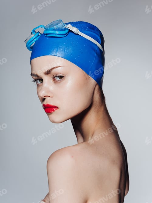 Preview: Portrait of a beautiful woman in a blue swimming cap red lips bared shoulders side view