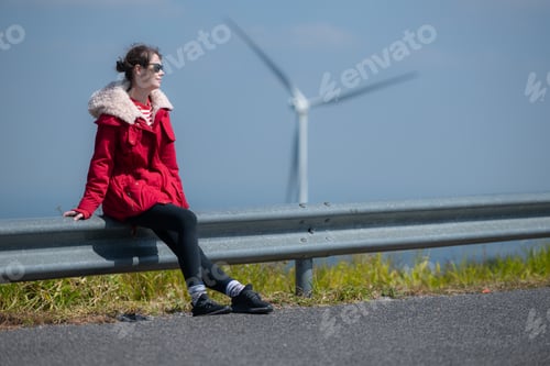 Preview: On the background of windmills, A young woman in a red jacket is enjoying her winter vacation.