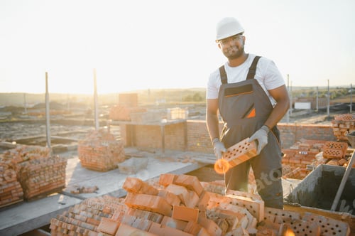 Preview: Portrait of an Indian construction worker in overalls and a hard hat at a construction site