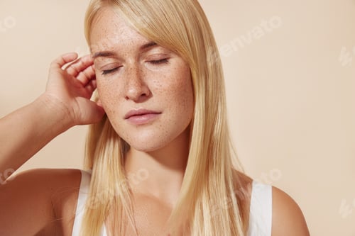 Preview: Young female with freckled skin standing with her eyes closed in studio