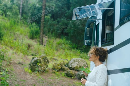 Preview: Woman standing against big camper van motorhome enjoying nature and serene day in travel