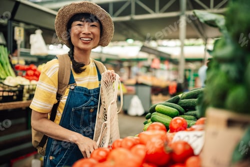 Preview: Smiling asian woman holding mesh bag at vegetable market stall