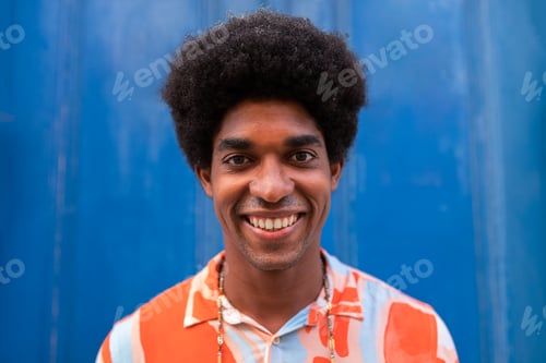 Preview: Headshot of smiling young African American man with afro hairstyle looking at camera.