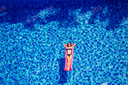 Preview: copy space spf and sunscreen beautiful brunette girl floating in the pool water.