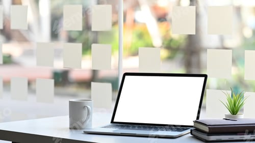 Preview: Computer laptop with white blank screen, potted plant, coffee cup and stack of books.