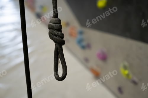 Preview: Close Up of a Safety Figure Eight Knot on a Black Climbing Rope at Indoor Bouldering Sport Gym