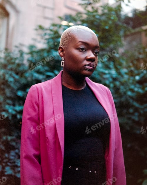 Preview: Young businesswoman wearing a pink jacket posing outdoors