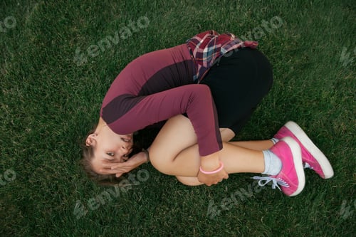 Preview: Scared young woman lying on the ground in city park