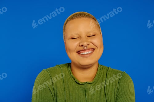 Preview: A cheerful young woman with a bright smile poses in front of a striking blue background