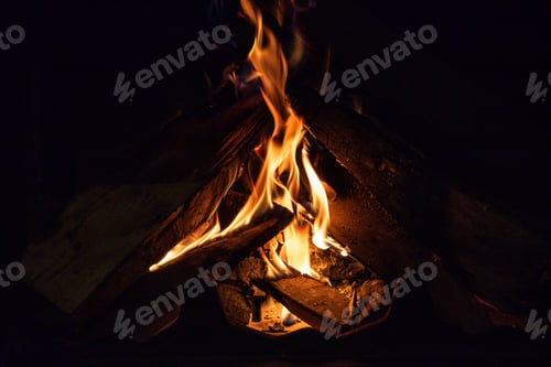 Preview: Winter with fireplace concept. Burning wood logs at fireside with colorful blazing as backdrop.