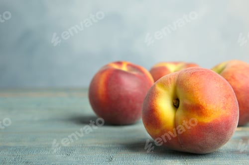 Preview: Fresh juicy peaches on wooden table against blue background, space for text