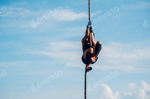Preview: Strong woman climbing a rope while participating in an obstacle course race